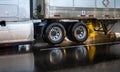 Big rig semi truck with a chassis with wheels carries cargo in a dry van semi trailer moving on a wet road slippery from rain Royalty Free Stock Photo