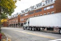 Big rig semi truck with day cab transporting cargo in dry van semi trailer driving on the city street road with red bricks Royalty Free Stock Photo