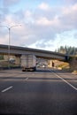 Big rig semi truck with dry van semi trailer going under the bridge across divided highway Royalty Free Stock Photo