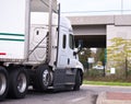 Big rig semi truck with dry van semi trailer turning on the circle under the bridge