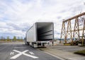 Big rig semi truck with empty refrigerator semi trailer with open door standing on the road shoulder in industrial warehouse area Royalty Free Stock Photo