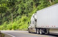 Big rig semi truck with high cab roof transporting cargo in dry van semi trailer running on the winding forest road in Columbia Royalty Free Stock Photo