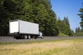 Big rig semi truck with long box trailer running on green road w Royalty Free Stock Photo