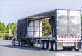 Big rig semi truck with open covered semi trailer unloading commercial cargo on warehouse parking lot Royalty Free Stock Photo