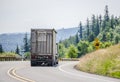 Big rig semi truck with semi trailer driving downhill on the turning road in Columbia Gorge area