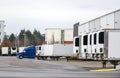 Big rig semi truck and semi trailers standing in row in warehouse dock for loading and unloading commercial cargo