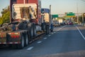 Big rig semi truck transporting another semi truck tractor on step down semi trailer on busy traffic highway