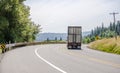 Big rig semi truck transporting cargo in semi trailer turning on the winding road