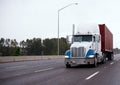 Big rig semi truck transporting container on straight wide highway in raining weather Royalty Free Stock Photo