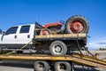 Big rig semi truck transports on the step down semi trailer small truck with old red tractor on its flat bed trailer Royalty Free Stock Photo