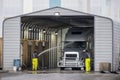 Big rig semi truck washes in covered car wash station with manual washing