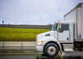 Big rig white day cab semi truck transporting goods in box trailer running on the wet road after the rain Royalty Free Stock Photo