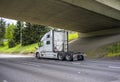 Big rig white diesel semi truck tractor running on the highway under the bridge going to warehouse for semi trailer pick up Royalty Free Stock Photo