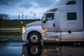 Big rig white semi truck tractor running on the night wet road with raining weather Royalty Free Stock Photo