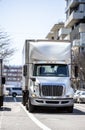 Big rig white semi truck with semi trailer delivery cargo to buildings in urban city street Royalty Free Stock Photo
