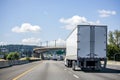 Big rig white semi truck transporting cargo in dry van semi trailer running on the wide highway road behind another traffic Royalty Free Stock Photo