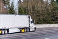 Big rig white semi truck transporting commercial cargo in dry van semi trailer driving on the straight wide highway road Royalty Free Stock Photo