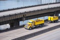 Big rig yellow tipper semi truck with dump trailer running on overpass intersection road along the river Royalty Free Stock Photo