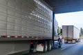 Different big rigs semi trucks with refrigerated and dy van semi trailers running on the wide highway under the bridge Royalty Free Stock Photo