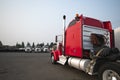 Classic big rig red semi truck tractor park on wide industrial p