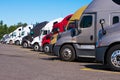 Big rigs semi trucks of different makes and models stand in row Royalty Free Stock Photo