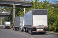 Big rigs semi trucks with dry van semi trailers parked on the street under overpass road intersection