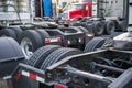 Big rigs semi Trucks with frames with rear dual drive wheels stand on the truck stop parking lot waiting for loaded trailers