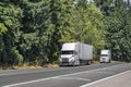 Big rigs semi trucks with reefer semi trailers standing in line on the highway entrance road shoulders in forest take a break for Royalty Free Stock Photo