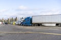 Big rigs semi trucks staing in row on wide truck stop parkink lot Royalty Free Stock Photo