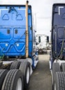 Big rigs semi trucks tractors standing in row on the parking lot waiting for loaded semi trailer for next delivery Royalty Free Stock Photo