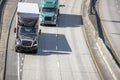 Big rigs semi trucks with semi trailers driving on merging road lines on wide highway