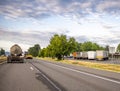 Big rigs semi trucks with semi trailers running on the road and standing for break on the rest area parking lot along the highway Royalty Free Stock Photo