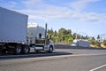 Big rigs semi trucks with semi trailers running towards each other in the opposite direction on the wide highway