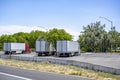 Big rigs semi trucks with semi trailers standing in row on the rest area parking lot along the highway road taking break according Royalty Free Stock Photo