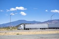 Big rigs semi trucks with semi trailers standing on small truck stop next to the highway road taking break for truck driver rest Royalty Free Stock Photo