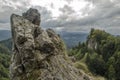 Big rock in foreground with cloudy sky and wooded mountain peak in background