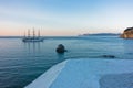 Big rock and sailing ship at sunset in front of city harbor, Skopelos island