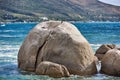 Big rocks in the blue ocean with mountains in the background. Stunning nature landscape or seascape on a summer day