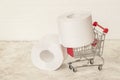 Big rolls of toilet paper in little trolley, mini cart. Consumer essential goods, hygiene, diarrhea, antipanic concepts