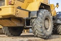 Big rubber wheels of soil grade tractor car earthmoving at road construction side. Close-up of a dirty loader wheel with a large Royalty Free Stock Photo