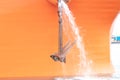 Big rusty anchor on orange with water flowing out of the boat ship in the harbor. Royalty Free Stock Photo