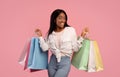 Big sale concept. Happy black young woman in casual clothes holding shopping bags over pink studio background Royalty Free Stock Photo