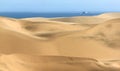 Big sand dunes. Ocean with ships and boat in background.