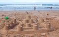 Big sandcastle on the beach with people playing