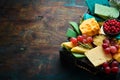 Big set of cheeses with snacks in a wooden box. On a black stone background. Royalty Free Stock Photo