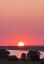 big setting evening sun over lake and forest in the distance Royalty Free Stock Photo