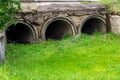 Big sewage drain pipe or effluent release wastewater into the sewage canal with green grass and litter around.