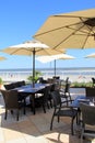 Big shade umbrellas over dining tables on outdoor patio at the beach