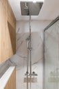 Big shower head and wooden finishing in interior of modern refurbished bathroom. Royalty Free Stock Photo