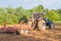 Big silver tractor with a red harrow disc cultivator in the field on a sunny day. The concept of work in a fields and agricultur